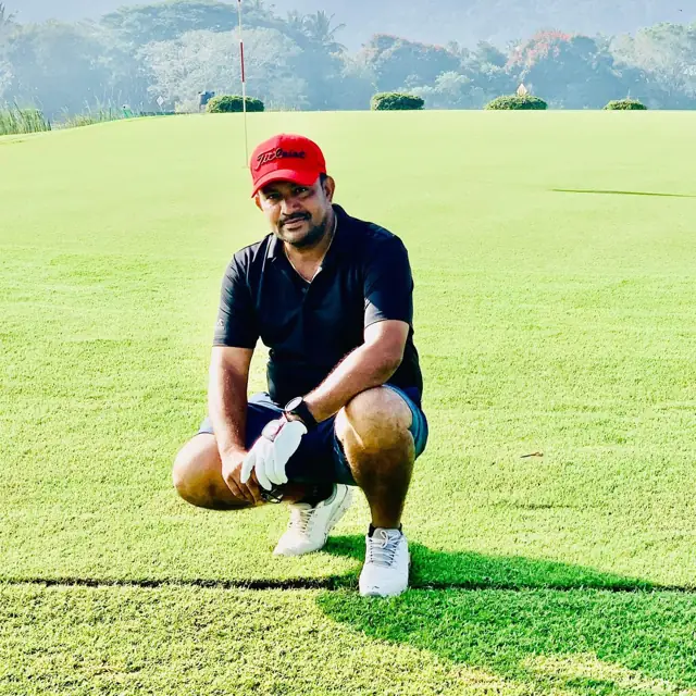 Tigers golfer kneeling on the green beside the pin